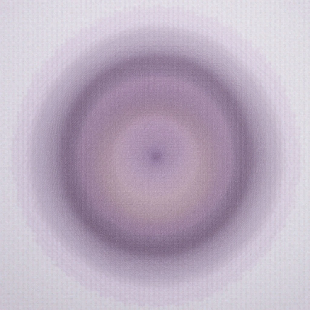 A soft, circular gradient dominates the image, shifting from a deep lavender at its center to pale lilac towards the edges. The shape appears slightly blurred and radiates outwards, creating an ethereal, almost glowing effect. A subtle texture is visible in the background surrounding the circle.
