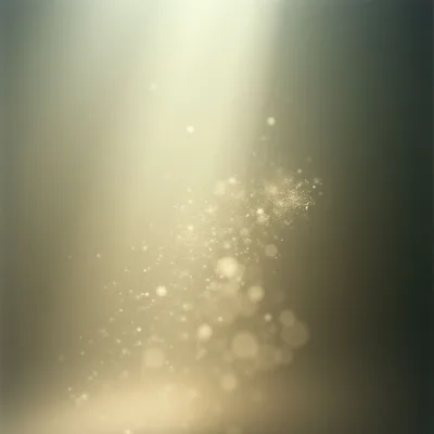 A stream of golden light illuminates a dark, muted background. Within the beam are countless tiny sparkling particles, clustered densely at the center and fading as they drift downwards. The overall effect is soft and ethereal, like dust motes dancing in a sunbeam.